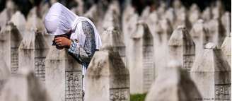 Uma mulher bósnia chora no túmulo de um parente que foi assassinado no genocídio de Srebrenica