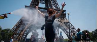 Turistas se refrescam com água diante da Torre Eiffel, em Paris
