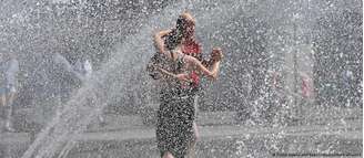 Casal dança em meio a refresco proporcionado por chafariz em Munique, sul da Alemanha