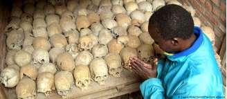Sobrevivente ruandês reza sobre ossadas de vítimas do genocídio em uma vala comum em Nyamata, Ruanda