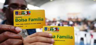 Beneficiários exibem cartões do Bolsa Família; programa contempla famílias com renda mensal de até R$ 178