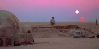 Luke Skywalker contempla um pôr-do-sol dobrado no planeta Tatooine, em uma cena clássica do primeiro filme Star Wars.
