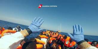 Refugiados em barco no mar Mediterrâneo são resgatados pela Guarda Costeira Italiana