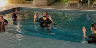 Lucas Paquetá ao lado da esposa, do atacante do Flamengo Pedro, e de um pastor durante realização do batismo