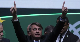 Bolsonaro com as duas mãos para o ar apontando para o céu