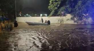 Moradores usam lancha para tentar resgatar pessoas ilhadas em enchente em Ubatuba