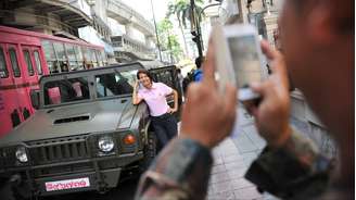 Militar tira foto de civil posando ao lado de jipe de guerra durante a lei marcial