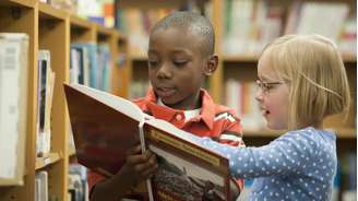 Garoto negro e garota branca em biblioteca