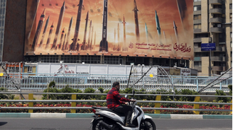 Motociclista passa por um outdoor anti-Israel com fotos de mísseis iranianos em Teerã, no Irã