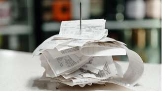 Notas fiscais empilhadas, após serem perfuradas em espeto de metal