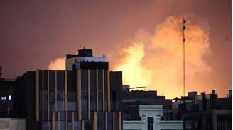 Fumaça saindo   atrás de prédios após uma explosão no segundo dia consecutivo de ataques dos EUA e de Israel, em Teerã.