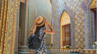 Mulher viajante usando vestido florido e chapéu no templo Wat Ratchabophit em Bangkok em um dia de verão