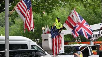 Um funcionário instala bandeiras em um poste de luz perto da Casa Branca, em antecipação à visita do Rei Carlos III da Inglaterra a Washington, D.C., em 25 de abril de 2026.