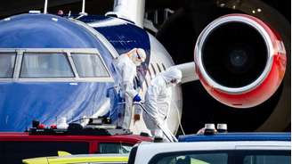 Pessoas usando roupas protetoras durante o desembarque de um avião