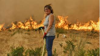 Uma mulher tenta apagar um incêndio em Santa Baia de Montes, no noroeste da Espanha, em 14 de agosto de 2025.