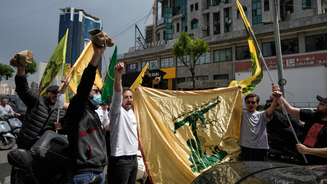 Apoiadores do Hezbollah agitam a bandeira da milícia pró-iraniana em 17 de abril de 2026 em Dahiyeh, um subúrbio de Beirute.