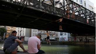 Jovens mergulham em canal em Paris, onde os termômetros marcaram mais de 30° e as temperaturas devem se manter elevadas durante toda a semana (25/05/26).