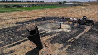 Agricultores resfriam área atingida por destroços de míssil perto de Najha, na Síria, após ataques no conflito entre Irã e Israel.