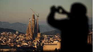 Um turista tira fotos da Basílica da Sagrada Família, que se torna a igreja mais alta do mundo em 10 de junho de 2026 após a instalação de uma seção de sua torre central, em Barcelona, na Espanha. Imagem de 30 de outubro de 2025.