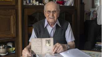 Albert Corrieri, então com 102 anos, mostra seu caderno de prisioneiro, o “vorläufiger Fremdenpass”, em seu apartamento em Marselha, no sudeste da França, em 21 de junho de 2024
