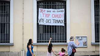Menina aponta cartaz em escola de Paris que denuncia calor de 35°C nas salas de aula, em 18 de junho de 2026.