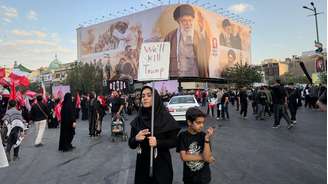 Mulher exibe cartaz com ameaças ao presidente dos Estados Unidos, Donald Trump, durante uma das homenagens fúnebres para o ex-guia supremo Ali Khamenei. 6 de julho de 2026