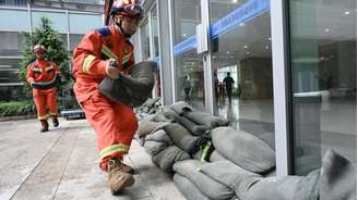 Bombeiros reforçam janelas e portas de um centro de evacuação com sacos de areia antes da chegada do tufão Bavi à província de Zhejiang; milhões de moradores foram retirados de áreas de risco, em 11 de julho de 2026.