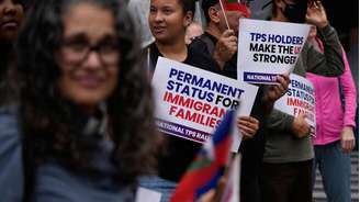 Pessoas seguram bandeiras haitianas e cartazes durante uma manifestação em apoio aos imigrantes que vivem nos Estados Unidos com o status de proteção temporária (TPS), na quinta-feira, 9 de julho de 2026, em San Diego.