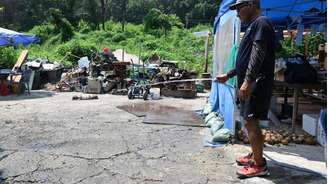 Para refrescar, homem umedece o chão na favela de Guryong, nos arredores do distrito de Gangnam, em Seul, em 4 de agosto de 2026, enquanto uma onda de calor escaldante continua a assolar a Coreia do Sul.