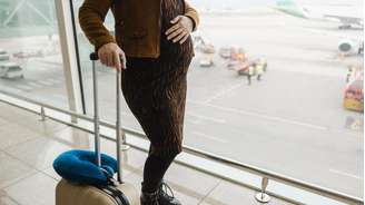 Imagem ilustrativa de uma mulher grávida com uma mala em um aeroporto.