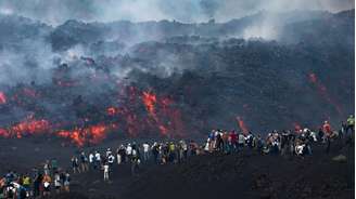 Visitantes próximo à uma corrente de lava, no Etna, na Sicília.