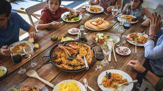 Pessoas comendo em volta de uma farta mesa de madeira