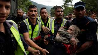 Policiais carregam um sobrevivente para um local mais seguro após uma enxurrada repentina em Trishuli, no Nepal