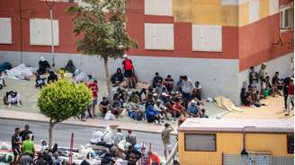 Os migrantes aguardam na calçada do bairro de Loma Colmenar, em Ceuta, em 27 de agosto de 2026.
