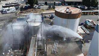 Equipes de bombeiros jogam água em um tanque superaquecido em Los Angeles, em maio