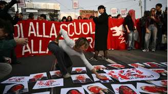 Estudantes cobrem com tinta vermelha imagens de Giuseppe Valditara, Elly Schlein e Giorgia Meloni, além do logotipo da empresa Leonardo, durante protesto em Turim contra o custo de vida e em defesa de mais investimentos na educação.