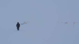 Eletricista caminha através de nevoeiro no isolado acampamento onde os cientistas se instalaram para analisar o gelo