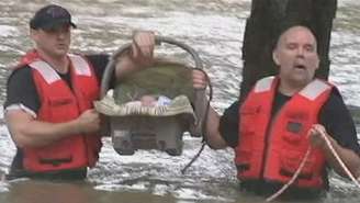 Socorristas carregam o bebê resgatado durante a enchente 