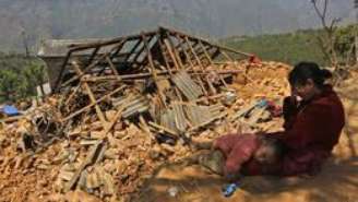 Mulher chora em frente à sua casa destruída (Foto: AP)