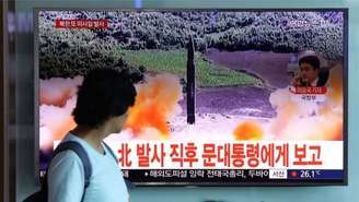 Mulher assiste a reportagem sobre o lançamento de míssil pela Coreia do Norte