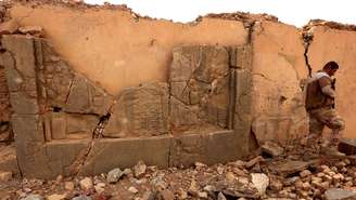 Um soldado caminha em meio a um artefato destruído em Nimrud 