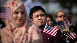 Novos cidadãos americanos agitam bandeiras do país durante cerimônia de naturalização