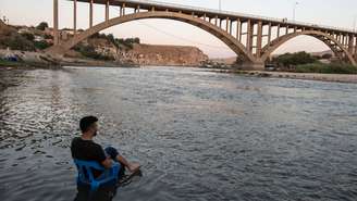 A calma antes da tormenta: um homem descansa nas margens do rio Tigre, enquanto as águas sobem lentamente para submergir seu povoado