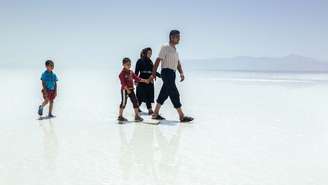 Família caminha pela crosta de sal seca e dura do outrora Lago Urmia, no Irã