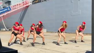 O grupo dançando twerk em frente ao novo navio de guerra australiano HMAS Supply