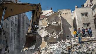 Palestinos inspecionam casa destruída, após ser atingida por ataques israelenses, na Cidade de Gaza, neste domingo