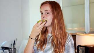 Jovem ruiva comendo abacate