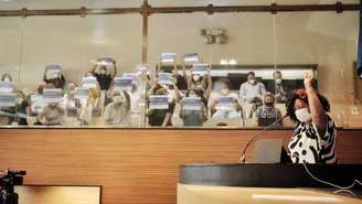 Imagem mostra a vereadora Dani Portela no canto direito falando durante plenária. Ao fundo, cidadãos sentados seguram placas escritas "Rua Marielle Franco"