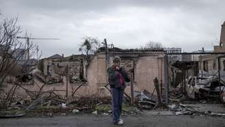 Mulher examina destroços de Bucha perto de Kiev