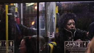 Foto mostra uma mulher negra dentro de um ônibus.